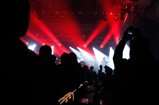 Audience members take out phones to snap photos of the band members.