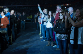 Audience members watch and take photos as Joel performs onstage.