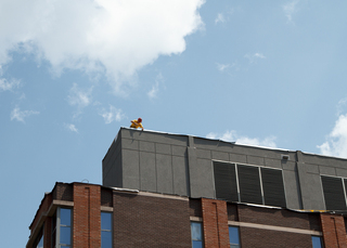 A construction worker installs roof liner to the top of the Center for Science and Technology building as crews replace its roof. This project is expected to be finished before fall classes begin. Photo taken Aug. 1, 2017